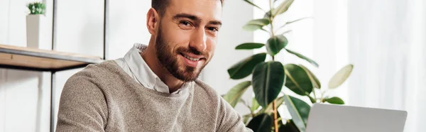 Sorrindo Homem Olhando Para Câmera Usar Laptop Casa Tiro Panorâmico — Fotografia de Stock