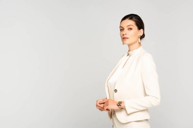 Beyaz takım elbiseli, kendine güvenen zarif bir iş kadını.