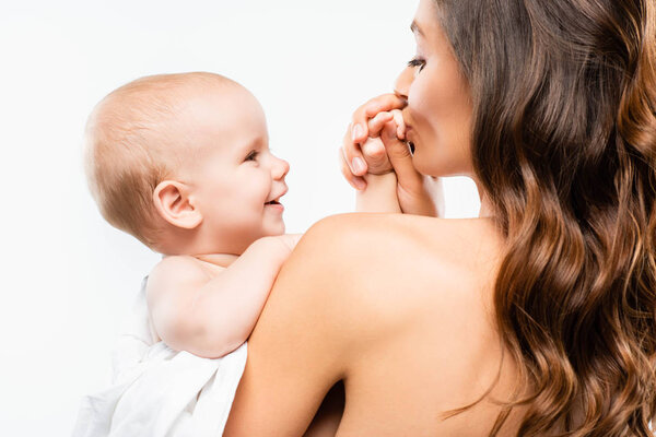 portrait of naked mother kissing hand of baby boy, isolated on white