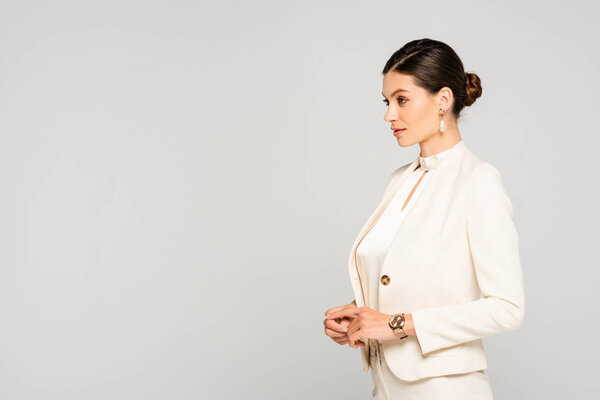 elegant confident businesswoman in white suit looking away, isolated on grey