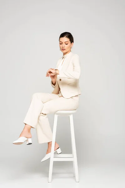 Élégante Femme Affaires Costume Blanc Regardant Montre Assise Sur Tabouret — Photo