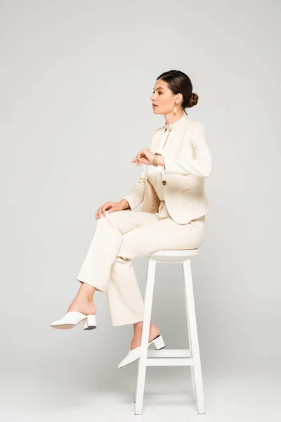 Élégante Femme Affaires Costume Blanc Assise Sur Tabouret Sur Gris — Photo