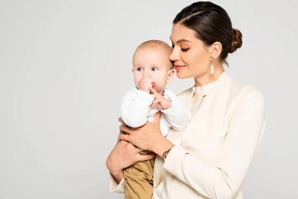 Atraente Mulher Negócios Positiva Segurando Bebê Menino Mãos Isolado Cinza — Fotografia de Stock