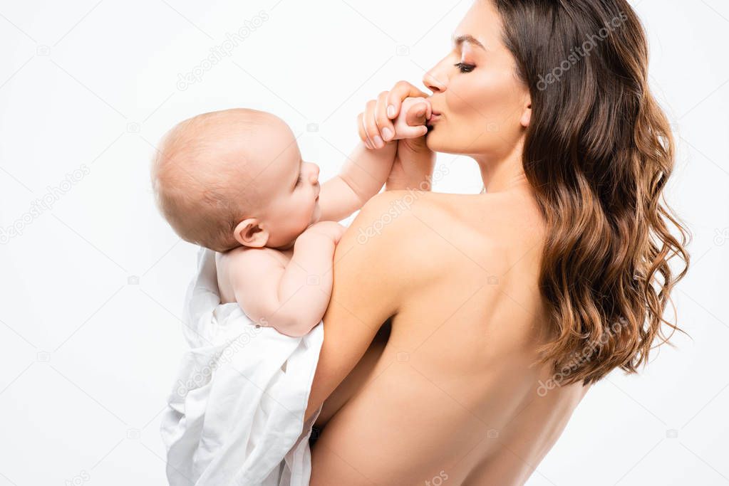 portrait of happy naked mother kissing hand of cute baby, isolated on white