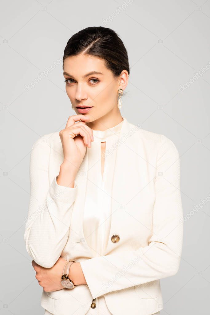 elegant thoughtful businesswoman in white suit, isolated on grey