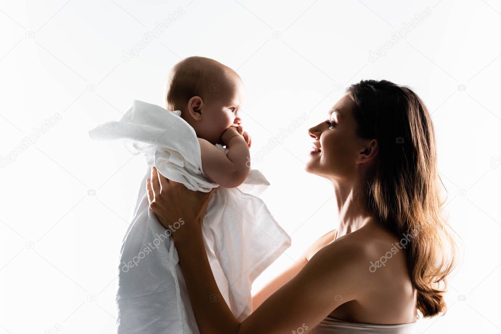 silhouette of smiling mother holding baby boy on hands, isolated on white