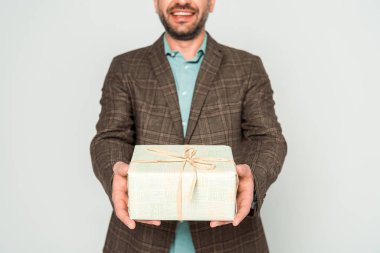 Gri renkte izole edilmiş, elinde hediye kutusu olan gülümseyen adam manzarası.