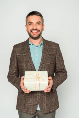 Mutlu adam, gri kameraya bakarken hediye kutusunu tutuyor.