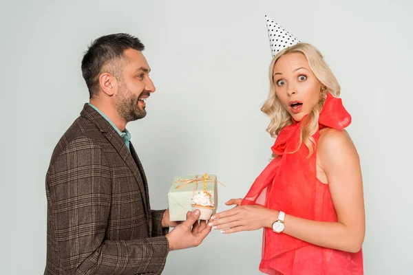 Surprised Woman Looking Camera Husband Presenting Gift Box Birthday Cupcake — Stock Photo, Image
