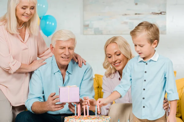 Happy Senior Man Holding Gift Box While Sitting Birthday Cake — Stock Photo, Image