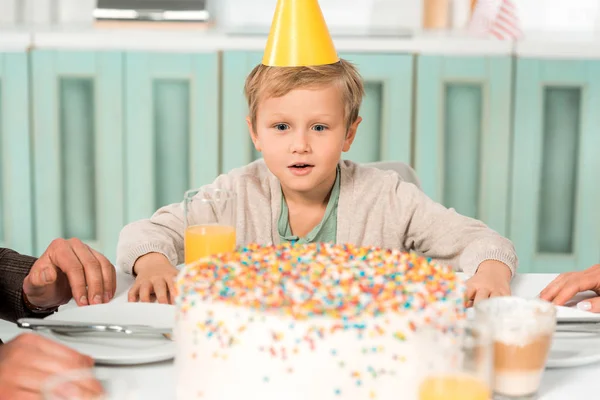 Избирательный Фокус Изумленного Мальчика Кепке Вечеринки Смотрящего Праздничный Торт Кухонном — стоковое фото