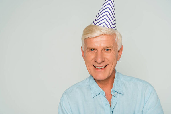 счастливый пожилой человек в кепке, улыбающийся в камеру, изолированную от серого
