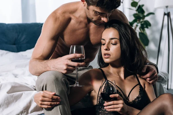 Sexy Mężczyzna Obejmując Uwodzicielski Dziewczyna Trzymając Kieliszki Czerwonym Winem — Zdjęcie stockowe