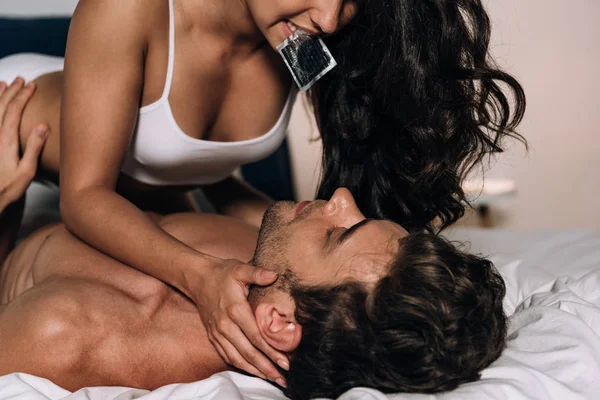 Cropped View Seductive Girl Holding Condom Teeth While Lying Man — Stock Photo, Image