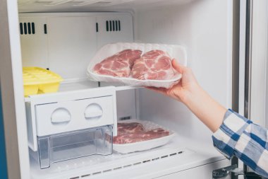 cropped view of woman taking out frozen meat from freezer clipart