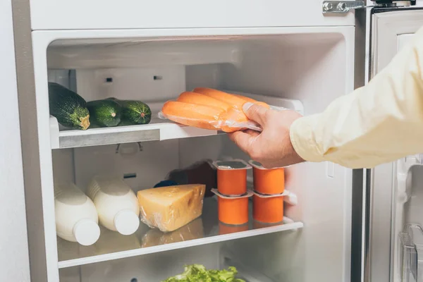 Cropped View Man Holding Carrots Vacuum Package Open Fridge Full — Stock Photo, Image