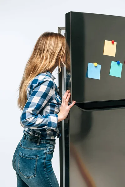 woman looking in open fridge with sticky notes isolated on white