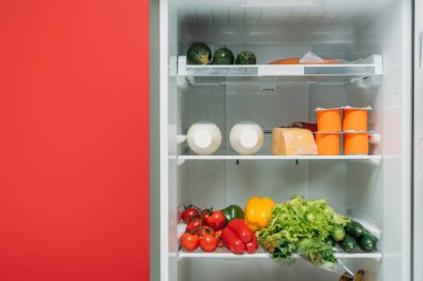 open fridge full of fresh food on shelves isolated on red clipart