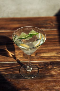 Buzlu, limonlu, limonlu margarita bardağı ve güneş ışığında ahşap yüzeyde şekerle süslenmiş.