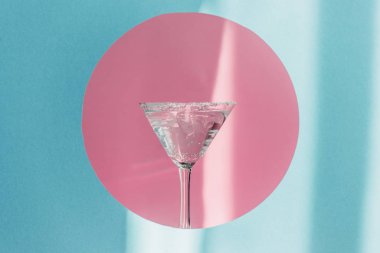 Cin tonik martini bardağında pembe çemberde mavi arka planda güneş ışığında
