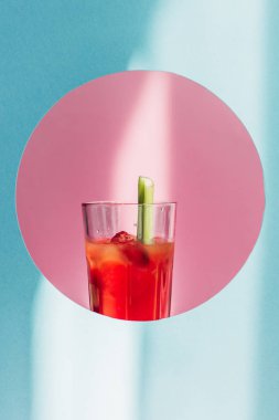 bloody Mary with celery in pink circle on blue background in sunlight clipart