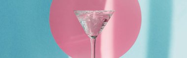 Cin tonik martini bardağında pembe çemberde mavi arka planda güneş ışığı, panoramik çekim