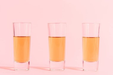 Pembe arka planda alkollü üç shot.