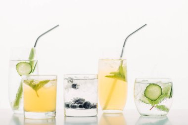 refreshing drinks with blueberries, celery, straws, mint, cucumber and ice isolated on white clipart