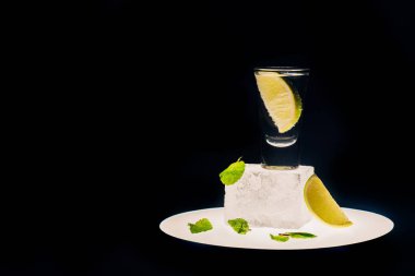 Limonlu taze tekila ve buzlu nane. Aydınlatılmış çemberde, siyah üzerinde izole edilmiş.