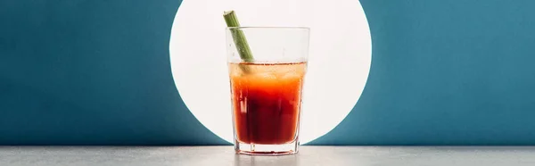 bloody Mary with celery on blue background with back light, panoramic shot