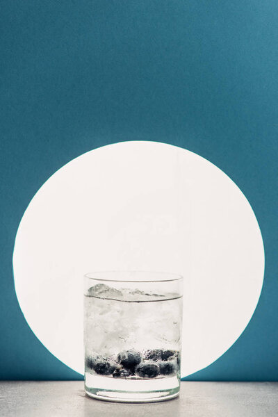 fresh gin and tonic in glass on blue background with back light