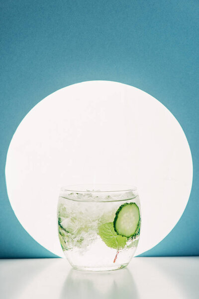 fresh gin and tonic with cucumber slices on blue background with back light