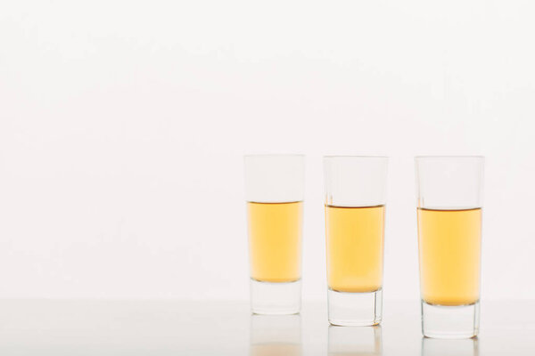 three shots with alcohol in row isolated on white
