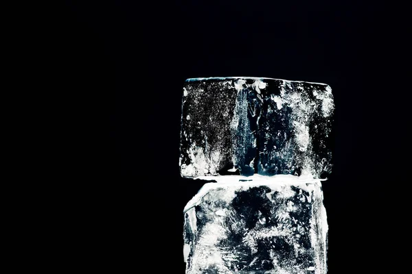 黒で隔離された正方形の氷の立方体を間近で見ることができます — ストック写真