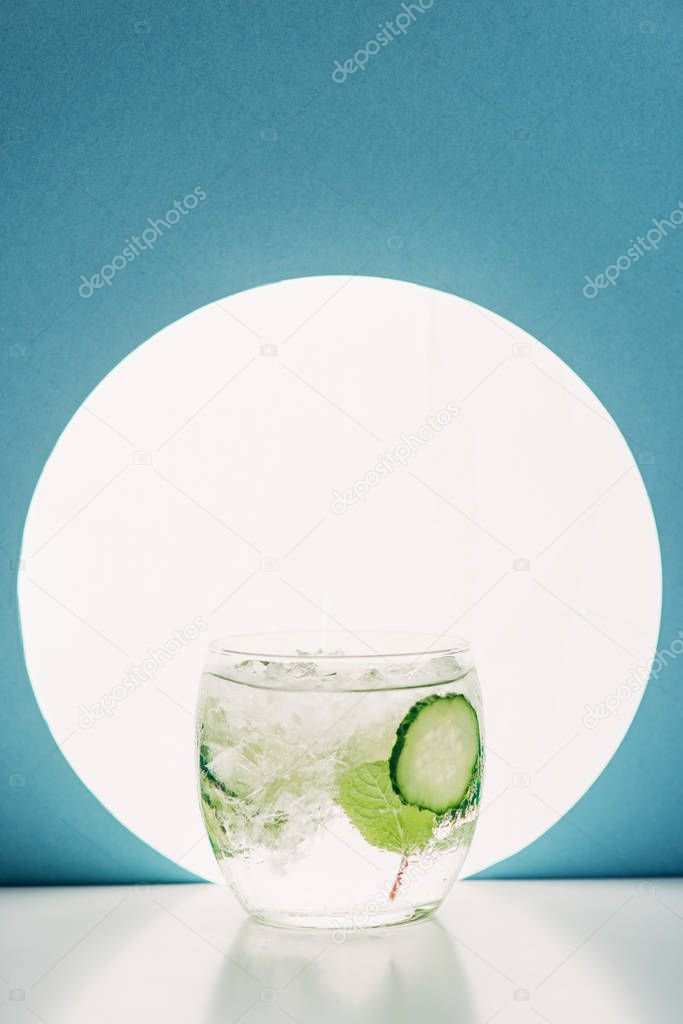 fresh gin and tonic with cucumber slices on blue background with back light