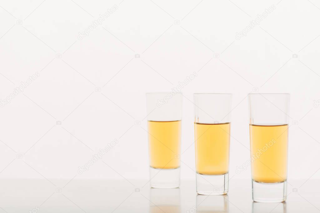 three shots with alcohol in row isolated on white