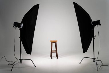 Wooden stool with studio light on grey background clipart