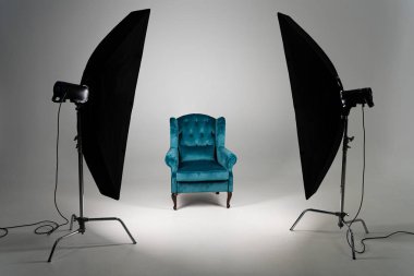 Blue armchair with studio light on grey background clipart