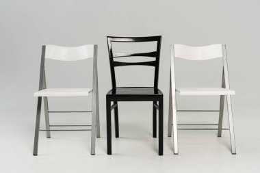 Three black and white chairs on grey background clipart