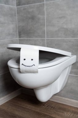Modern banyodaki beyaz klozetin üzerinde gülümseme işareti olan tuvalet kağıdı.