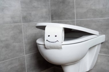 Toilet paper with smile sign on toilet bowl in restroom clipart