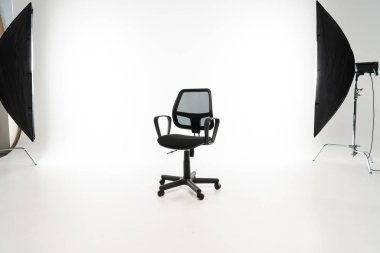 Black office chair with studio light on white background clipart