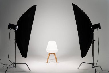 Gri arka planda stüdyo ışığı olan beyaz modern sandalye.