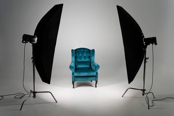 Blue armchair with studio light on grey background