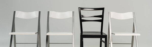 Black and white chairs isolated on grey, panoramic shot