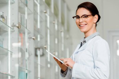 Çekici eczacı dijital tablet kullanırken kameraya gülümsüyor