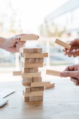 KYIV, UKRAINE - NOVEMBER 22, 2019: cropped view of women playing blocks wood tower game  clipart