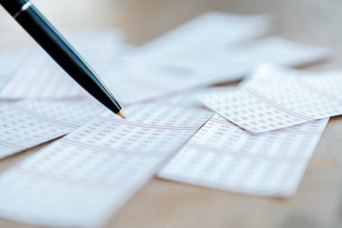 Masadaki loto biletlerinin yanındaki kalem seçici odak noktası