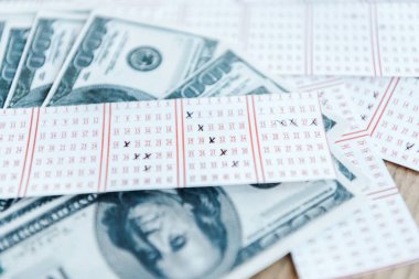 Masadaki dolar banknotlarının yanındaki işaretli piyango biletlerinin seçici odak noktası