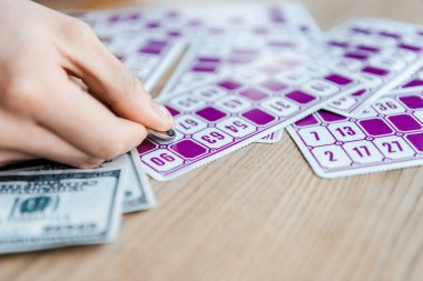 cropped view of woman holding coin and scratching lottery ticket near cash  clipart